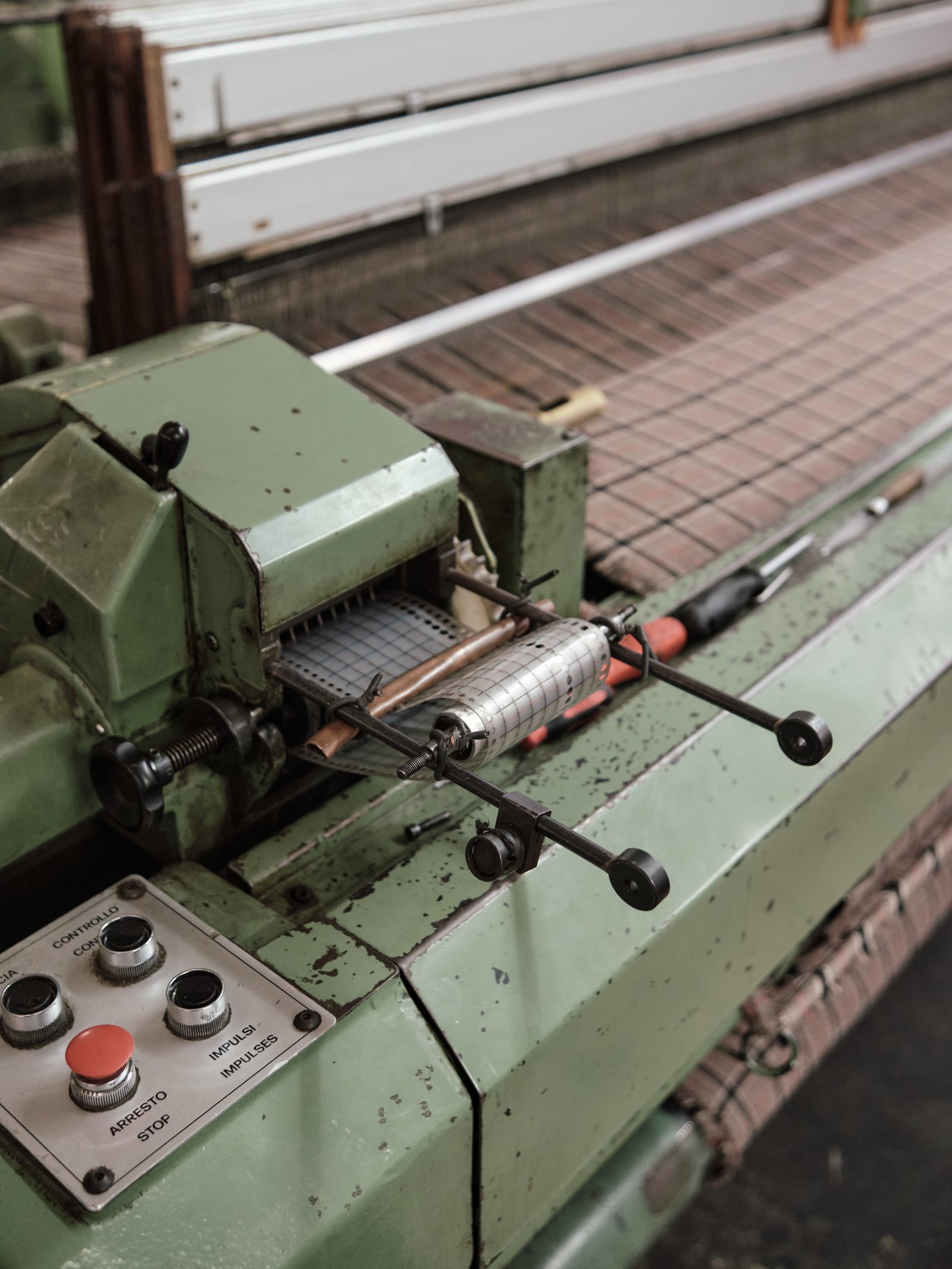 Due to the loom’s age, factories have developed expertise in repairing these machines, which have long outlived the manufacturer’s official support. It’s common to see improvised fixes, as seen in this punch card feeder, which is secured with wires and an additional metal piece. The punch card itself determines the fabric’s pattern, guiding the loom’s intricate weaving process. Photo taken at Eco Lã