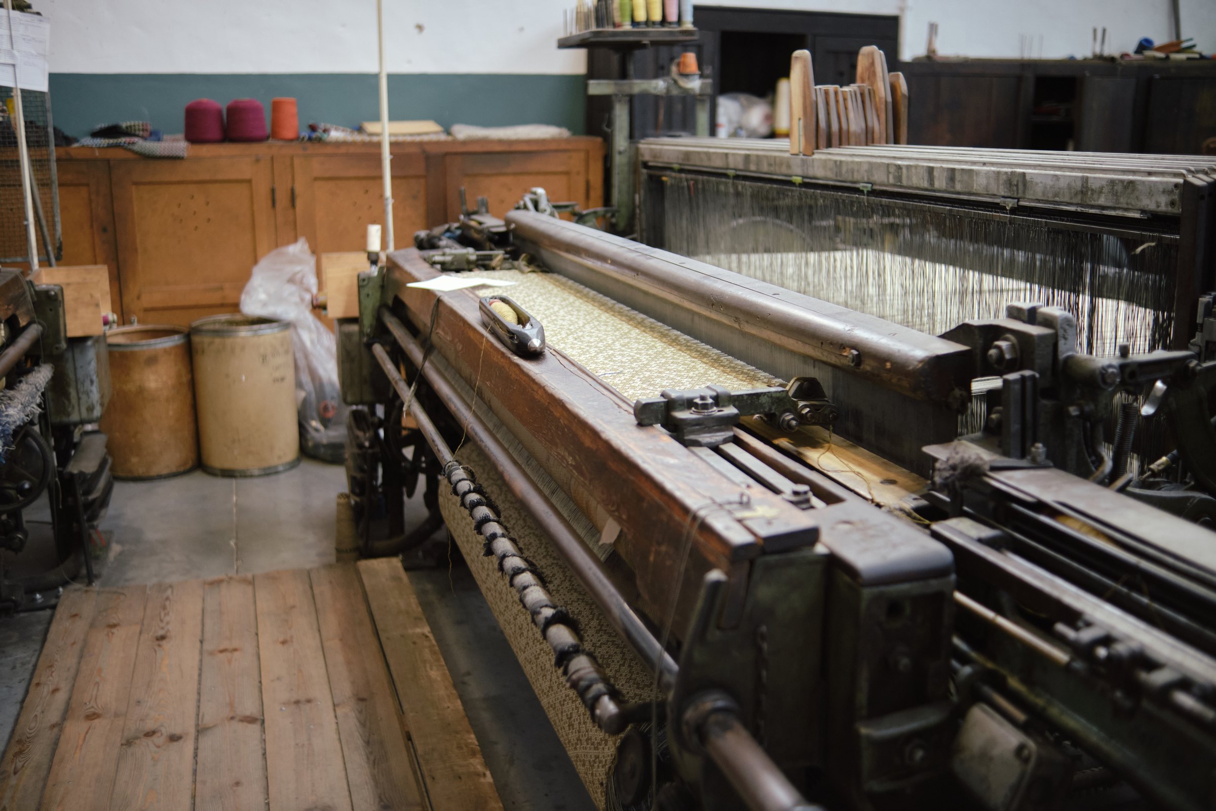 The wooden piece on top of the loom is called a shuttle. It moves at an incredibly high speed across the loom, carrying the wool thread from one side to the other. Its motion is so rapid that it’s nearly impossible to see with the naked eye. Photo taken at Burel Factory