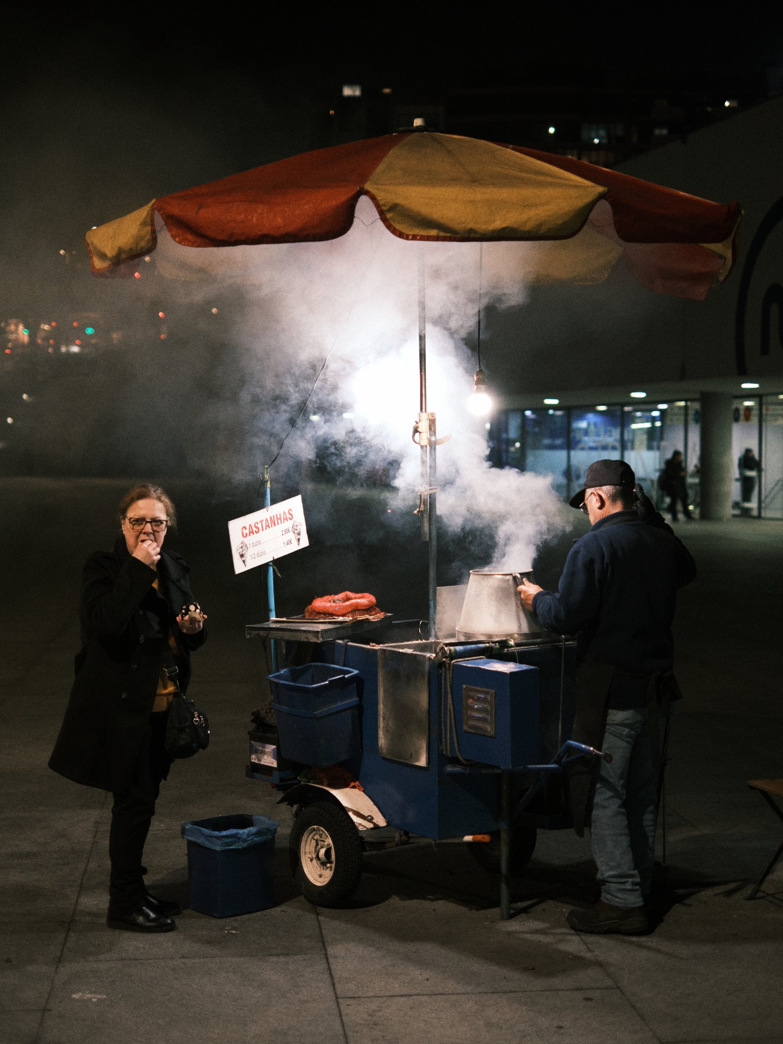 Roasted chestnut stands are typical throughout Portuguese cities and here we can see a customer enjoying a pack of freshly roasted chestnuts by the metro station. 🇵🇹 Trindade, Porto
